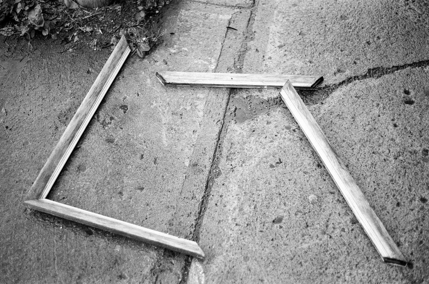 a broken wooden picture frame
on a wet sidewalk