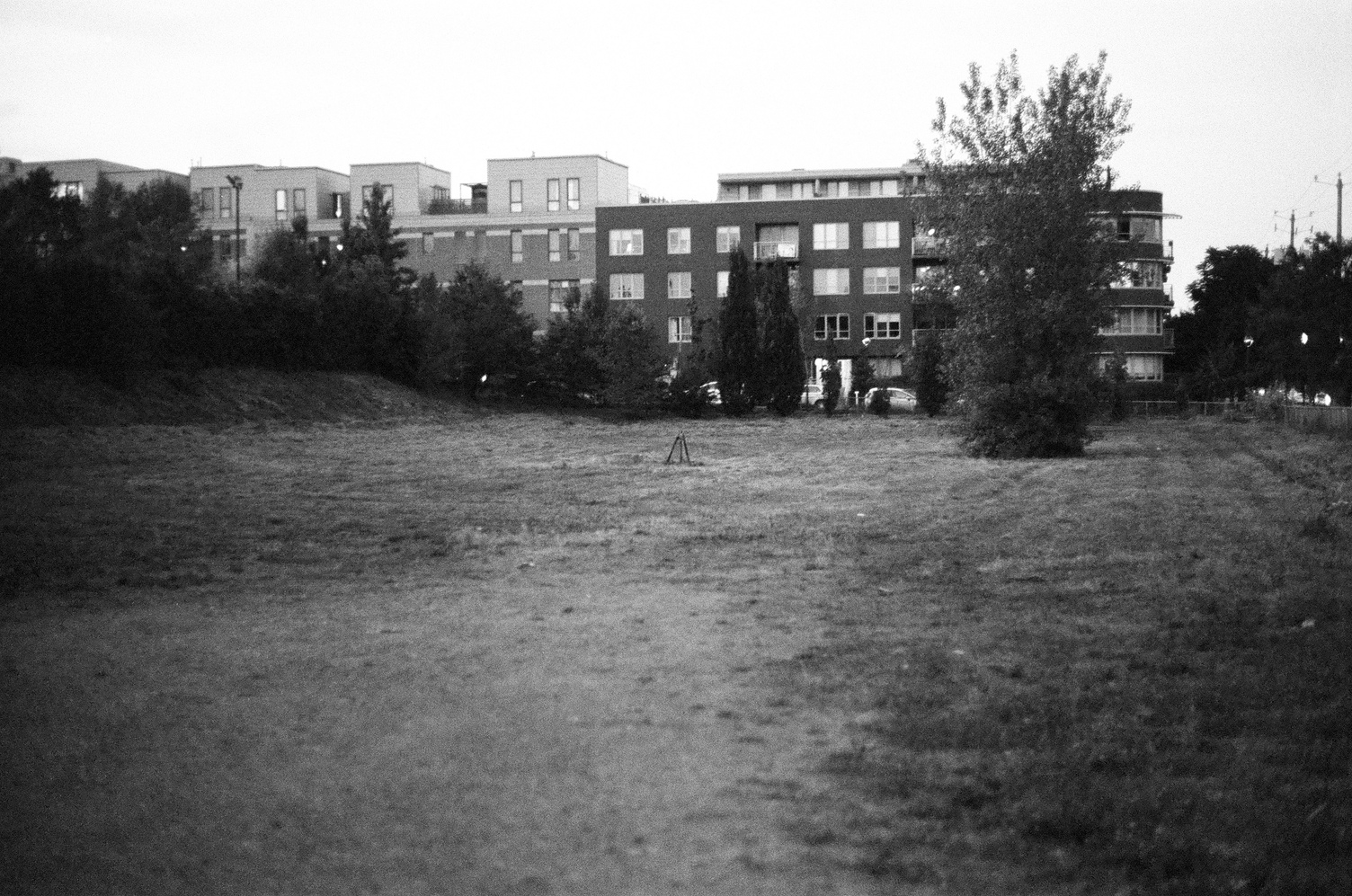 an empty field with some sort of small tripod structure
in the middle.
beyond it are condo buildings.