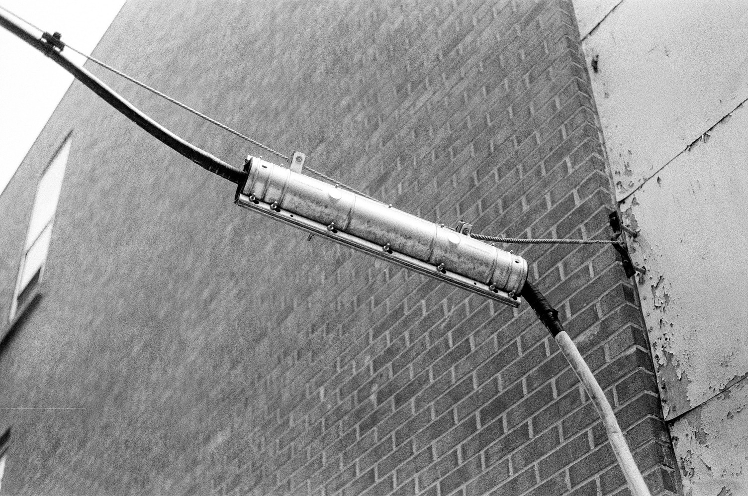 a metal cylinder
with a thick cable going through it
suspended against a brick wall
by a smaller steel cable
bolted into the wall.