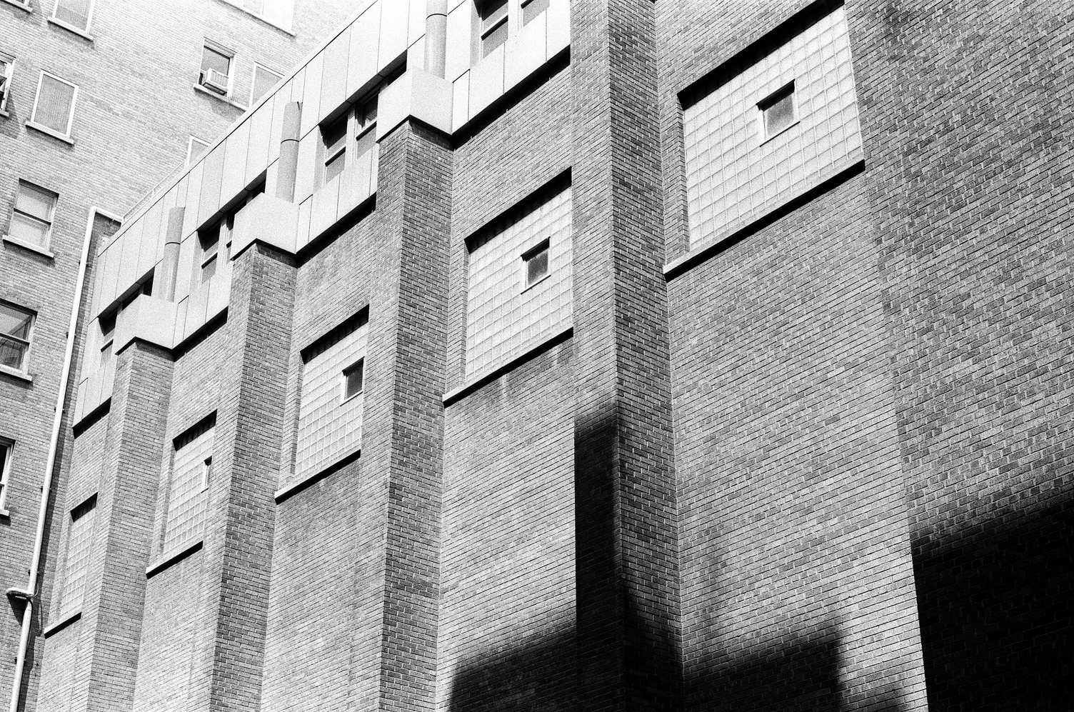 the side of a brick building
that is featureless until a couple storeys up
where there are squares of glass cube grids
with small actuall windows
embedded in them off-centre.
the windows are separated by columns of bricks
that go down the outside of the building.