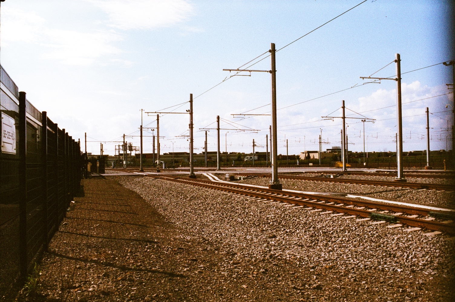 train tracks with overhead lines
inside a fenced area.
there are three parallel tracks.