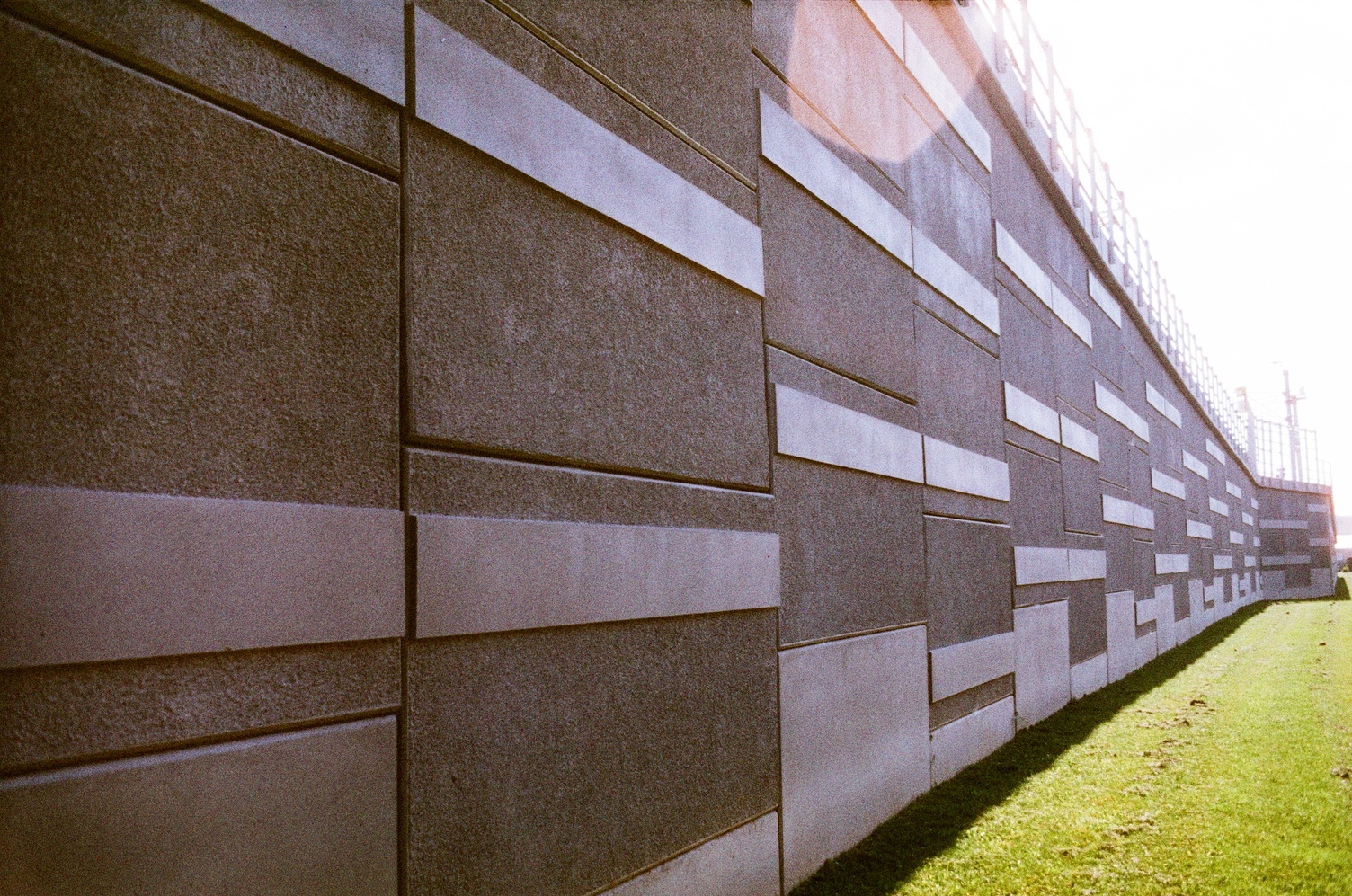 the wall of the base under a track,
close at the left side of the frame
and quickly stretching into the distance
to the right.