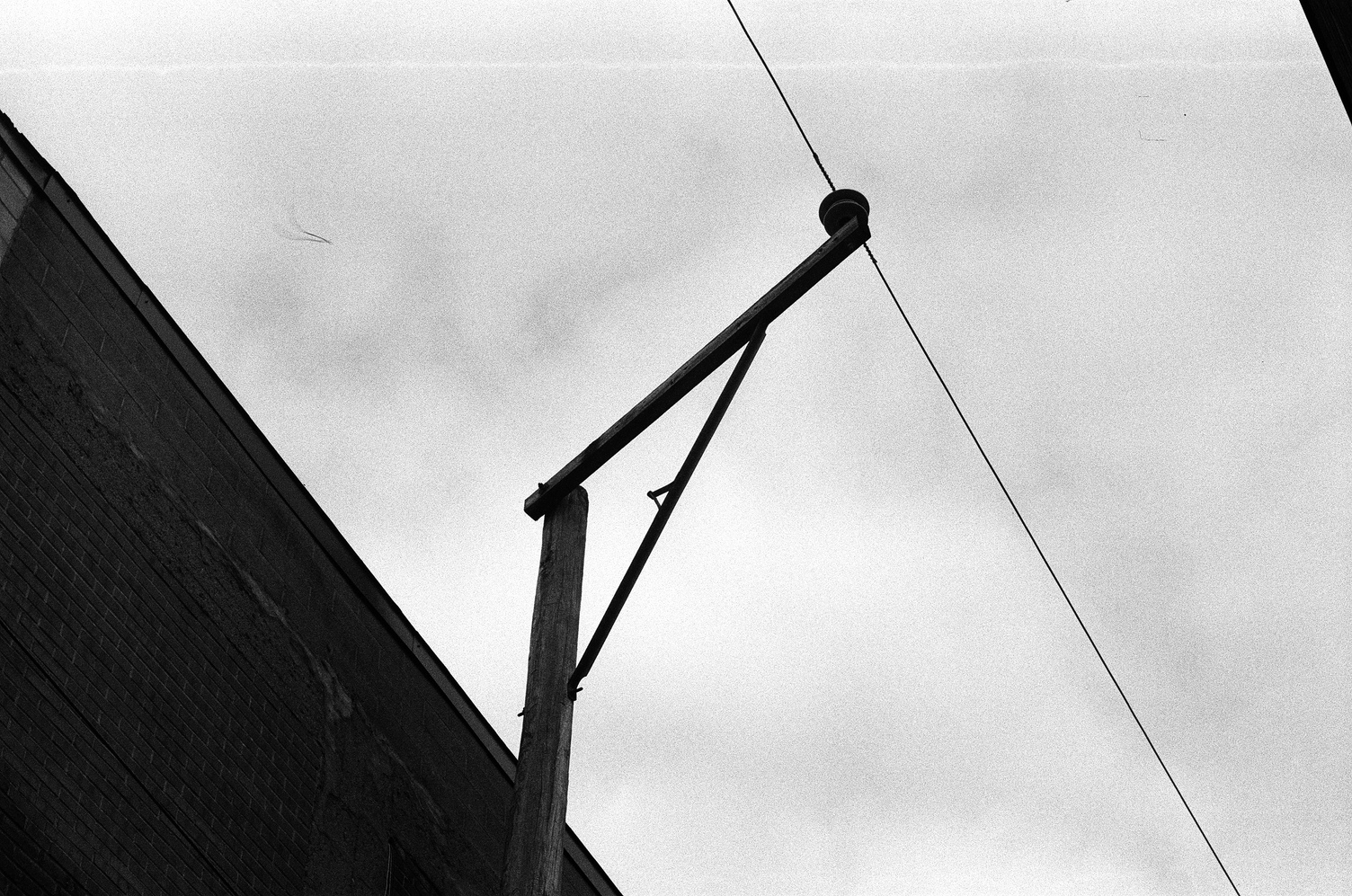 a single cable,
probably telephone,
suspended by a pole
in an upside-down L shape
with a truss between
the two pieces.