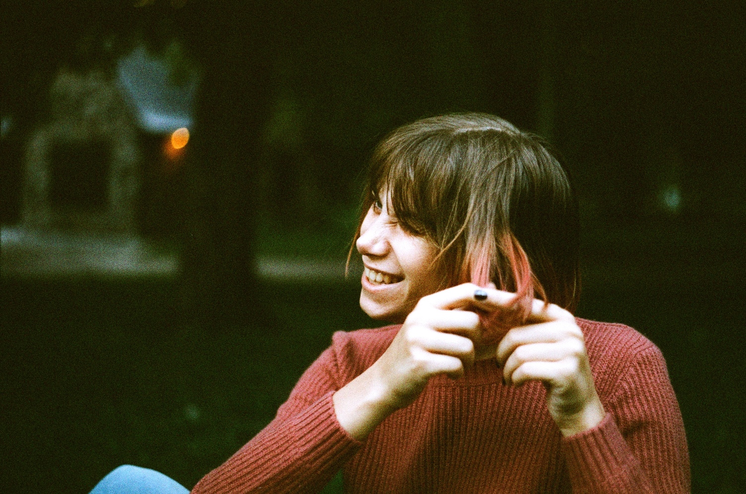 Ayla in an orange sweater
pulling her fingers through her hair
and making a squinting face.