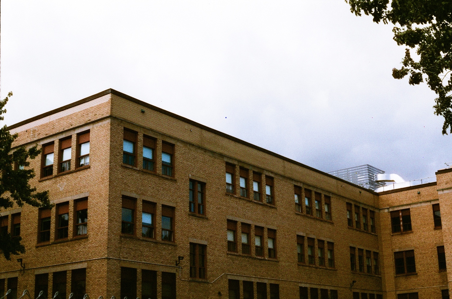 a light brown or beige brick school building
with its rows of windows.
the trim around the windows is sort of red-brown.