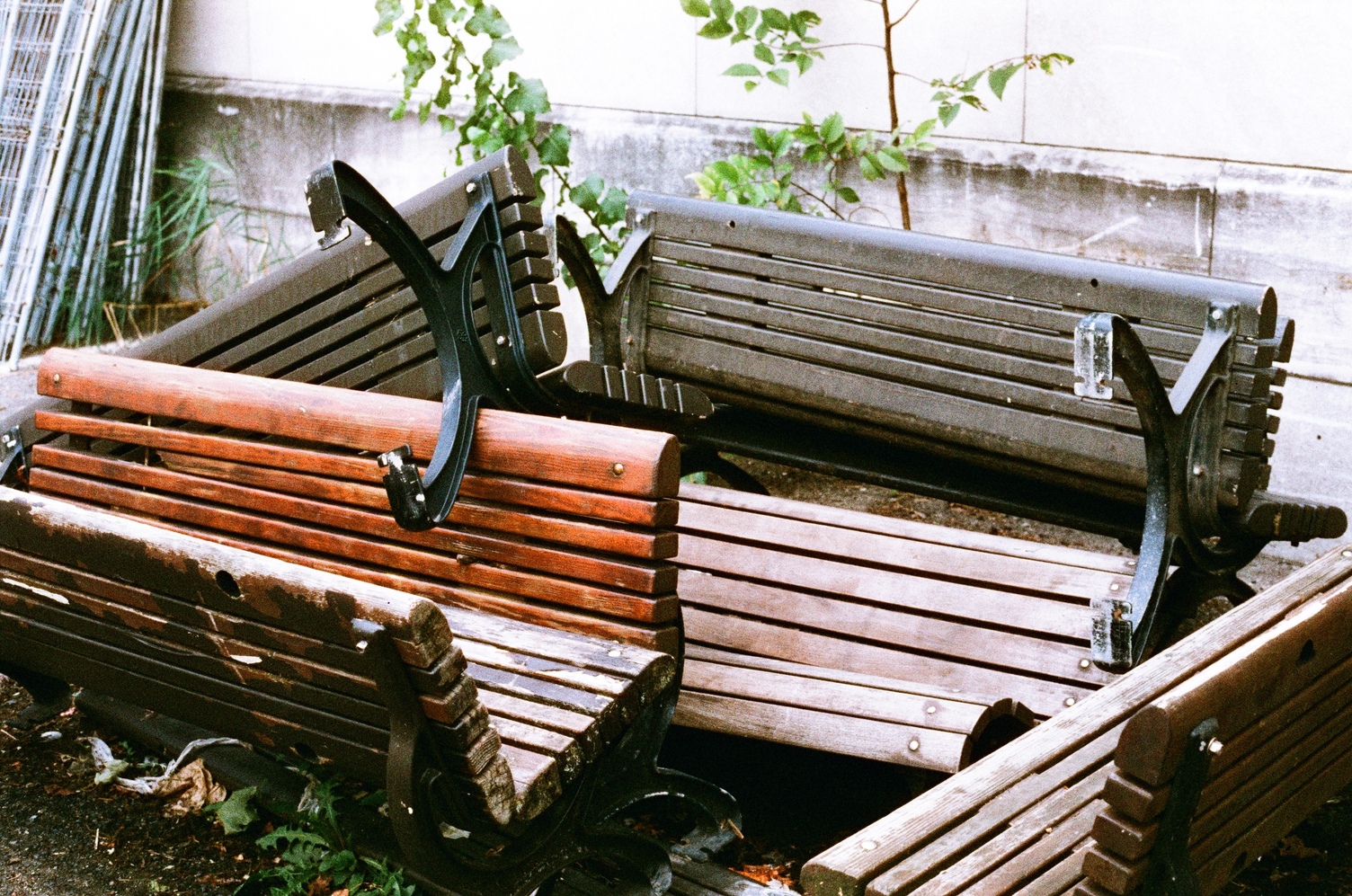 a haphazard pile of broken and discarded park benches.
they're nice ones made of wooden slats and black metal supports.
some are nice warm brown and others are more grey.