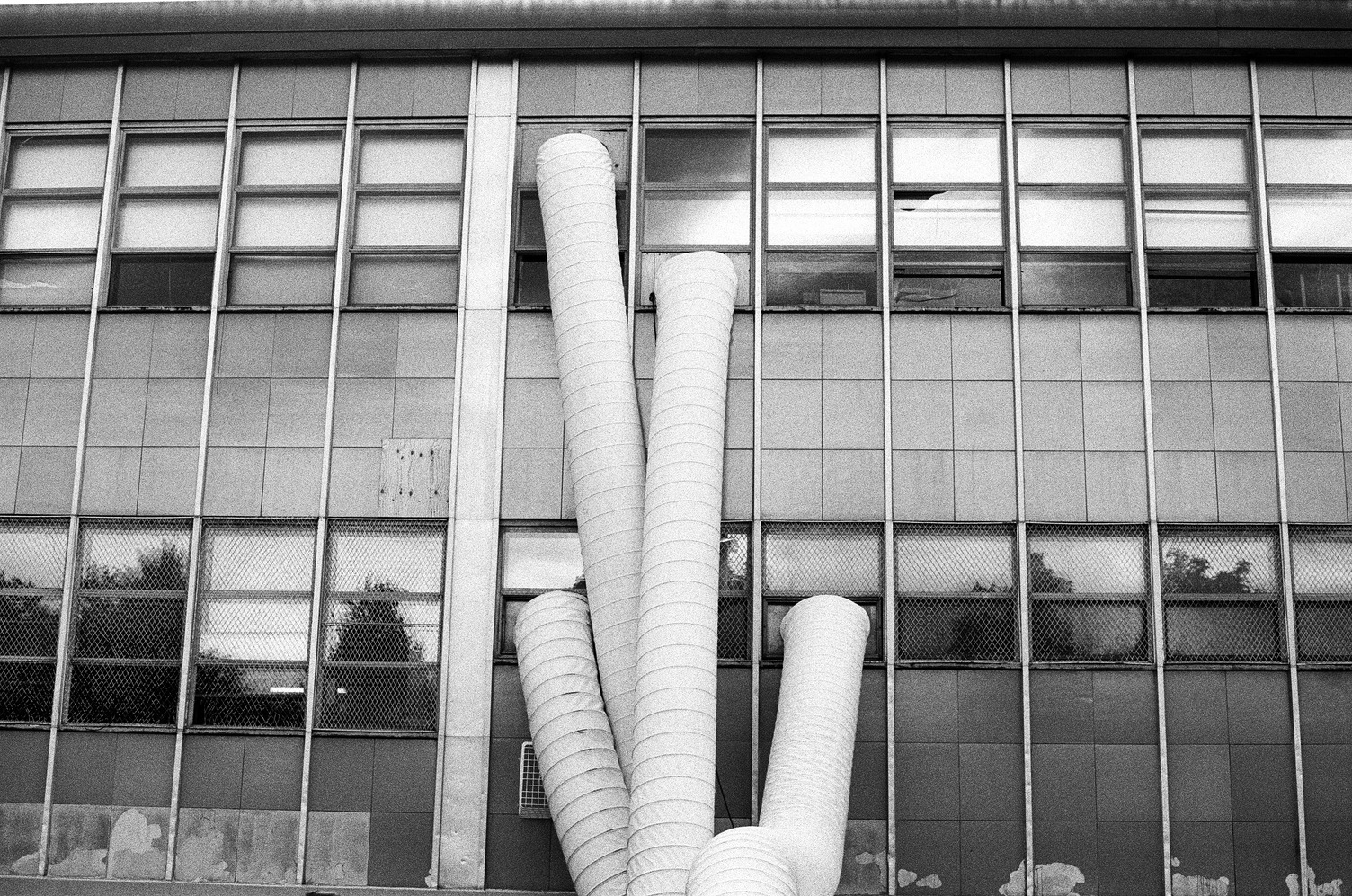 four large flexible fabric tubes
coming out of various windows
in the side of a school building.