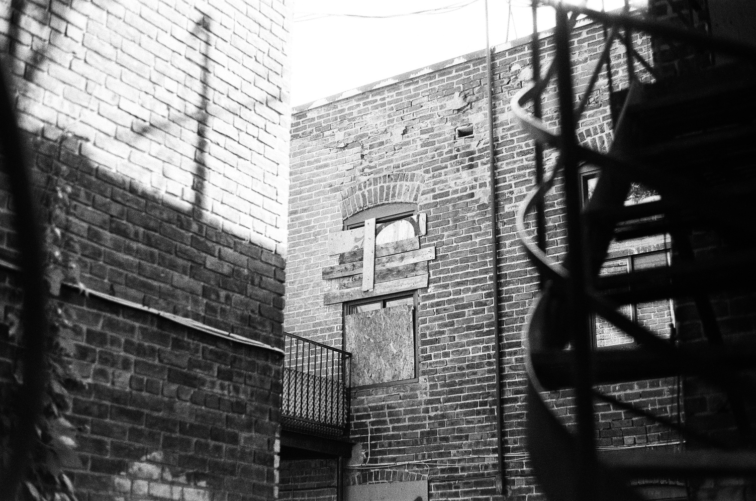 a view into the interior courtyard
of an abandoned building
with a haphazardly boarded up window.