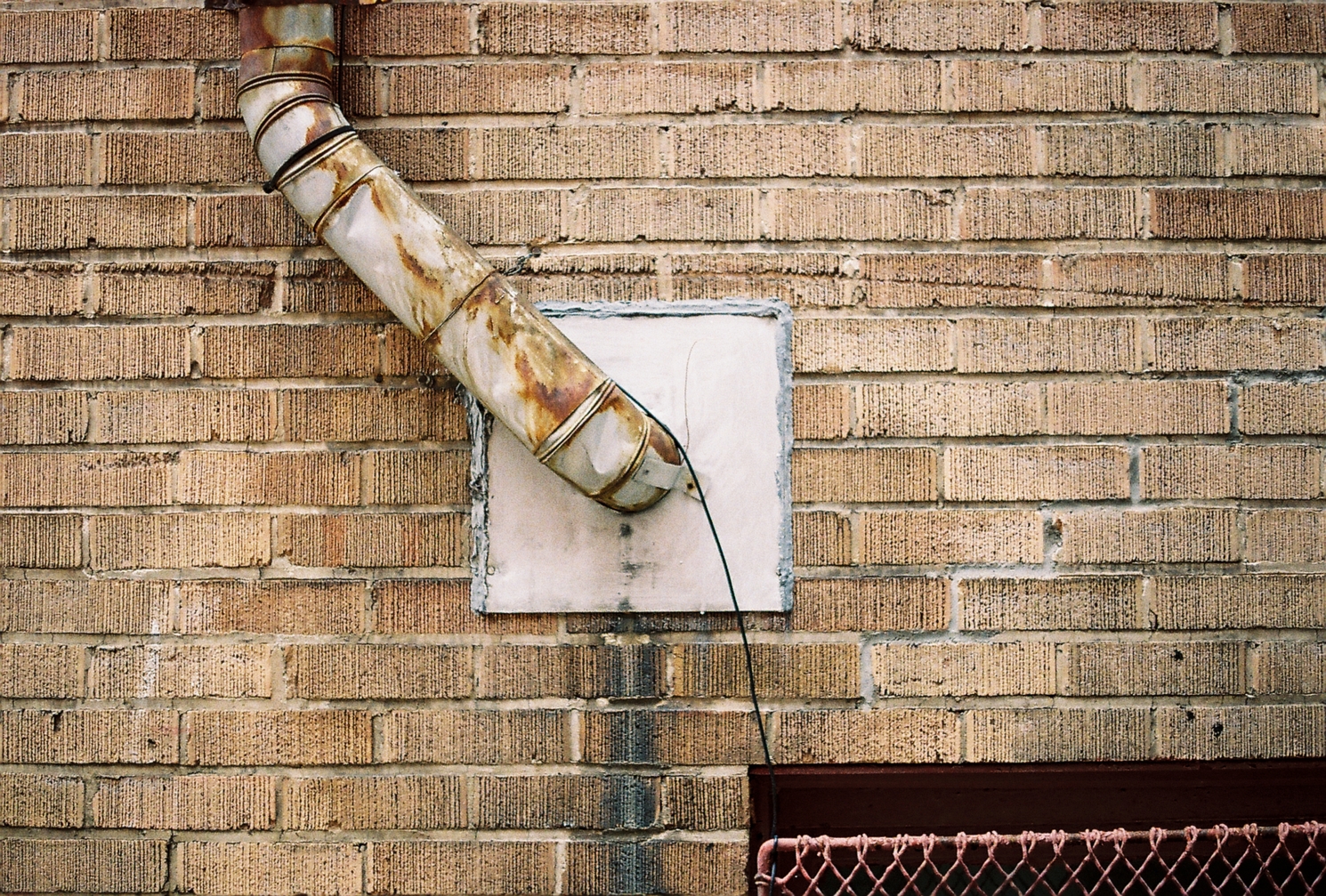 an old friend:
the pipe coming out of a square patch
in a yellow brick wall
that I've photographed before on digital.
the pipe comes out at an angle
towards the top left
then straightens out towards the top of the frame.
in the bottom right
there's the top of a window grate.