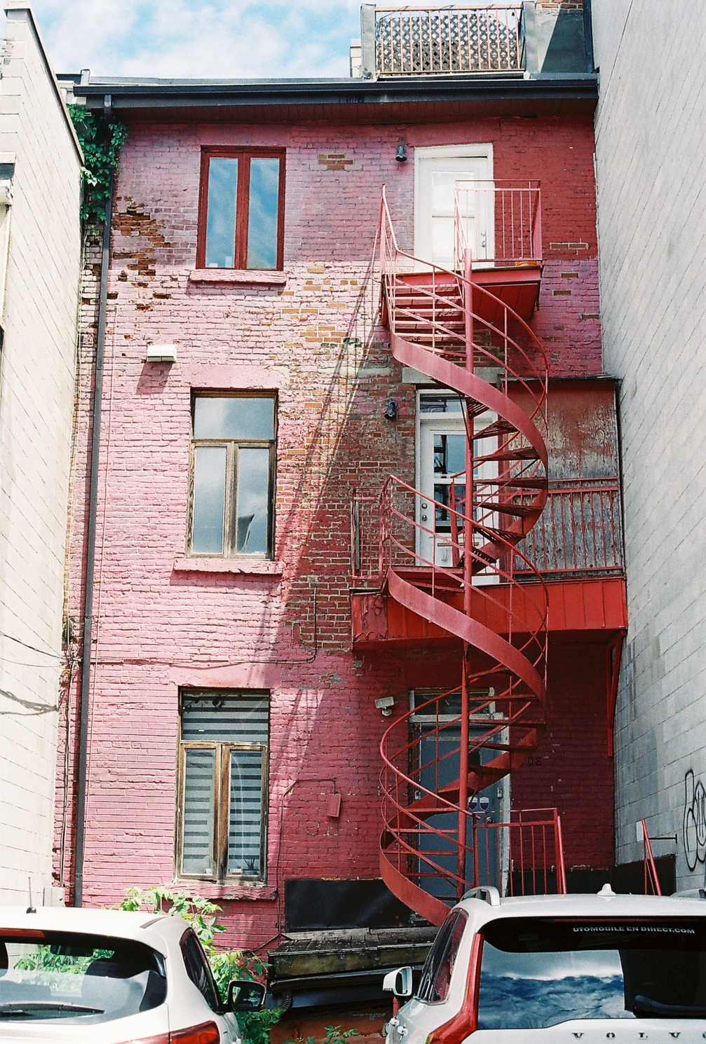 a familiar sight:
the back of a brick building
painted in red
and fading unevenly to pink.
a spiral staircase descends
past three doors on the right,
and there are three windows on the left.