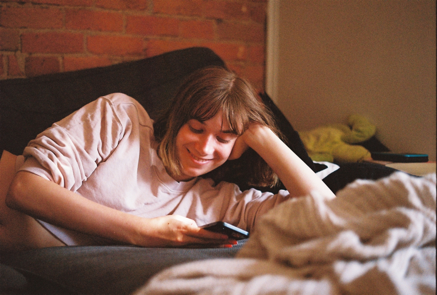 Ayla lying on the couch,
head propped up on her arm,
smiling at her phone.